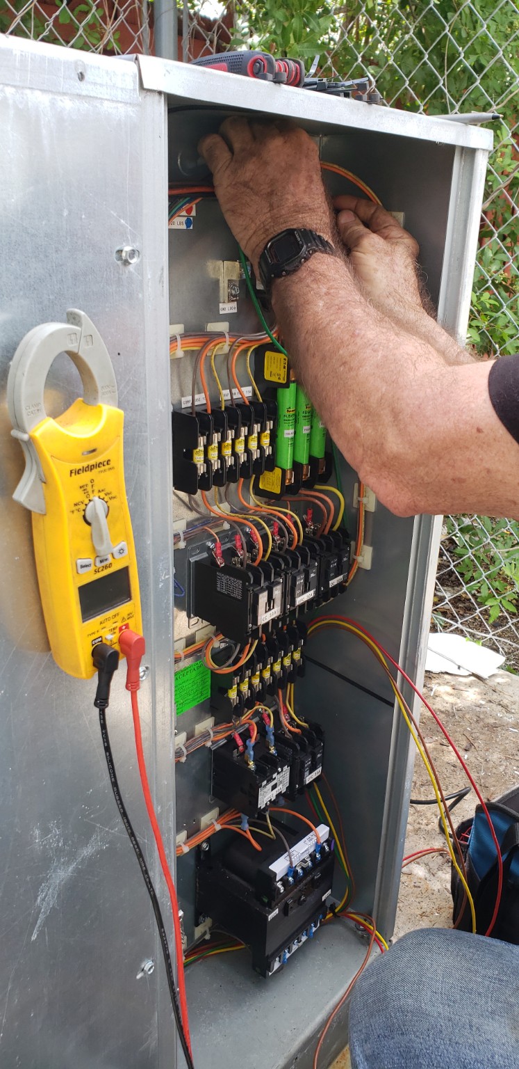 Technician performing electrical control-panel work on commercial refrigeration equipment